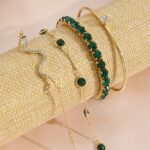 Pulseiras de cobra Concept Áurea com strass verde compondo um look elegante.